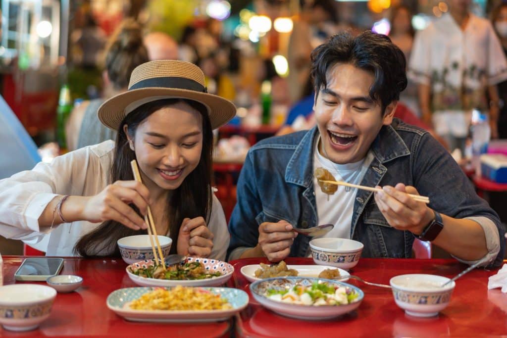 Couple enjoying authentic street food at a night market, perfectly reflecting budget dining tips for travelers seeking local flavors.