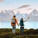 Couple with backpacks admiring breathtaking Nordic mountain landscape by the water, representing the best Nordic country to visit for nature lovers