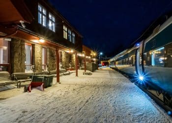 Snow-covered platform at a European train station at night with a modern night train ready for boarding — perfect scene capturing night train Europe travel.