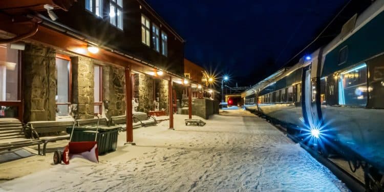 Snow-covered platform at a European train station at night with a modern night train ready for boarding — perfect scene capturing night train Europe travel.