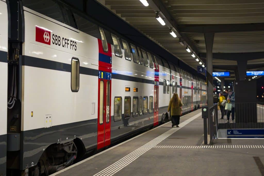 Modern double-decker night train in Europe at a lit station platform with passengers boarding , representing efficient and scenic night train Europe travel.