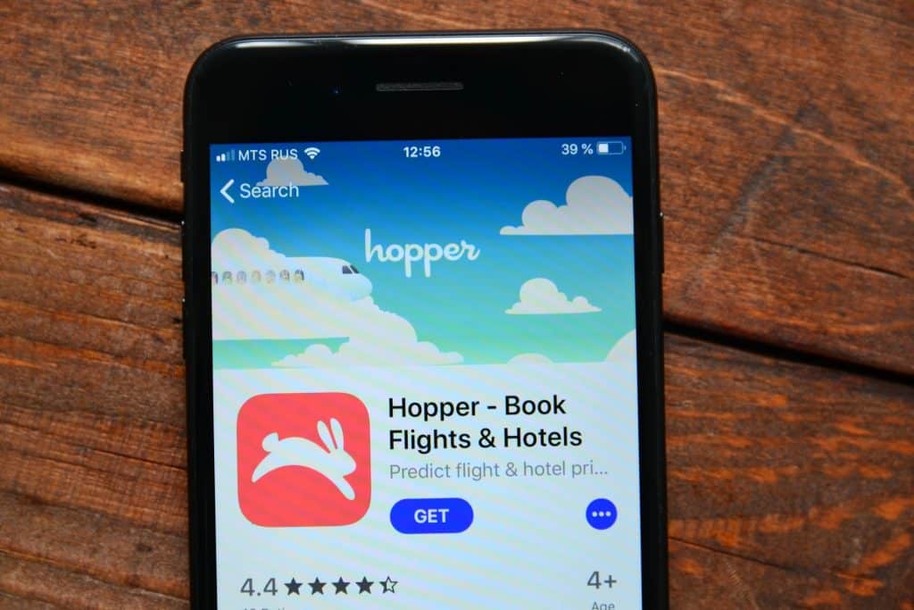 Hopper app open on a smartphone, showing flight and hotel booking options, illustrating tips for cheap flights using travel apps.