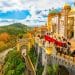 Colorful view of Pena Palace in Sintra, one of the best cities in Portugal, with lush green hills and visitors exploring the historic castle on a bright day.