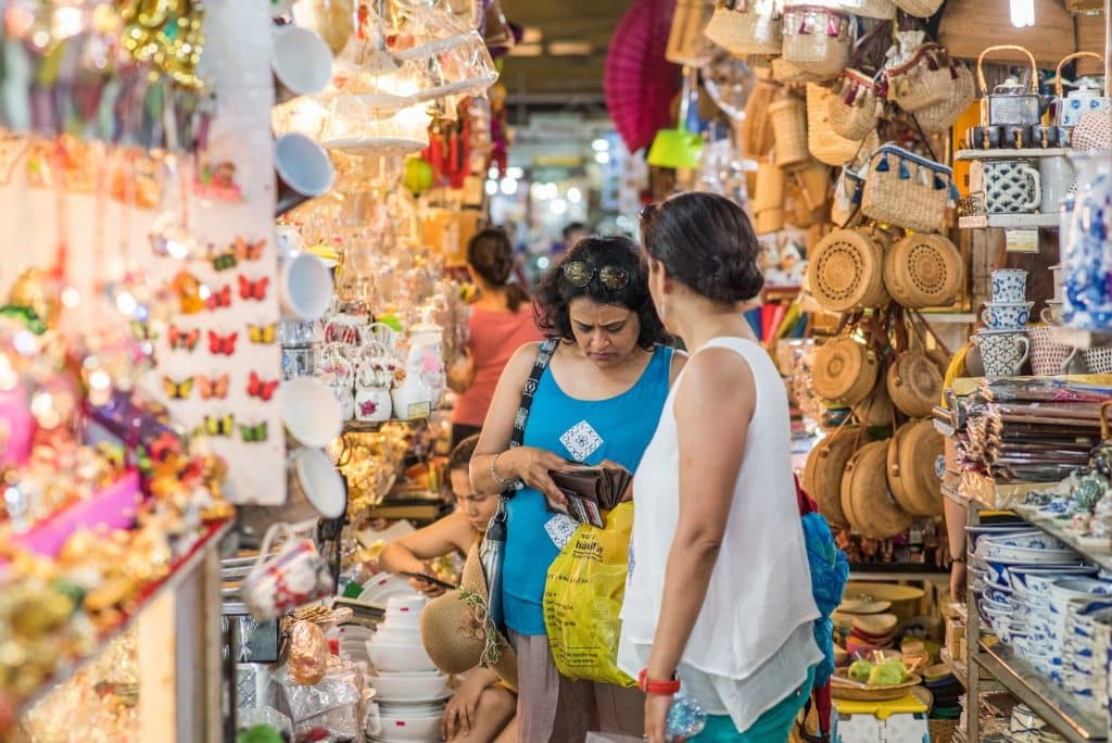 Woman at a crowded tourist market looking surprised at high souvenir prices — a real example of how common tourist traps catch travelers off guard.
