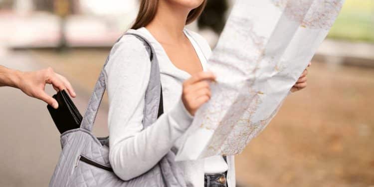 Tourist checking a city map while a pickpocket reaches into her bag, a reminder to stay alert and avoid tourist scams when exploring new places.