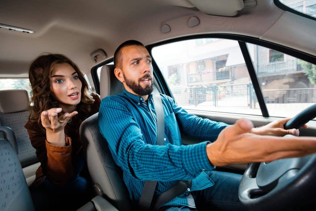 Frustrated tourist arguing with a taxi driver over inflated fare, showing why you must learn how to avoid tourist scams with local transport.