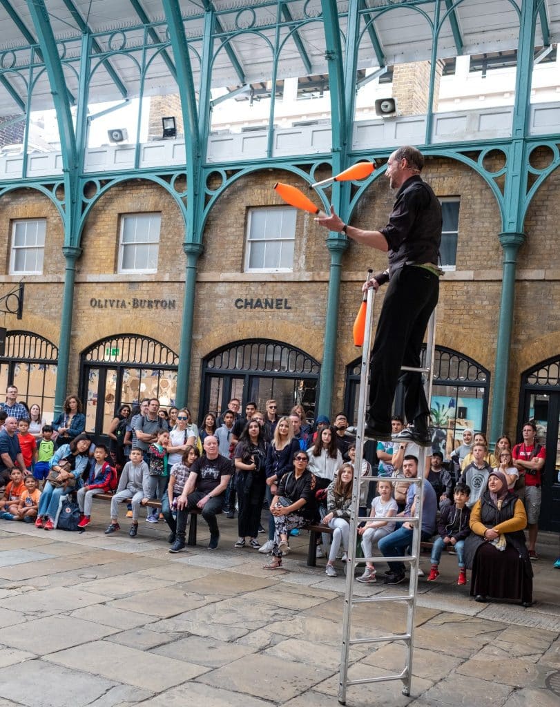 Street performer juggling in front of a large crowd, an example of how distractions can be used to trick travelers unless they know how to avoid tourist scams.