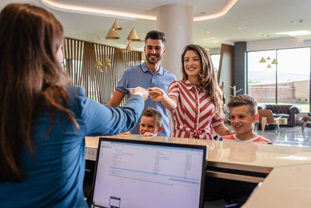 Family checking into hotel reception using points from best travel loyalty programs.