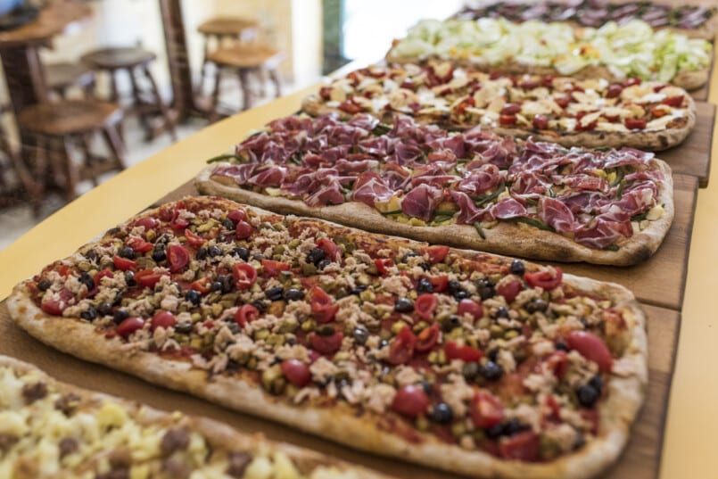 A variety of pizzas on a wooden table showcasing the cheap food options available in Europe.