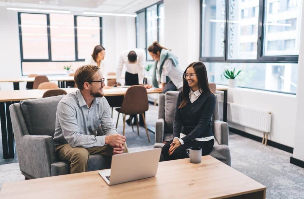 Two professionals chatting in a coworking space, showing more nomads and how remote workers connect and collaborate while living abroad.