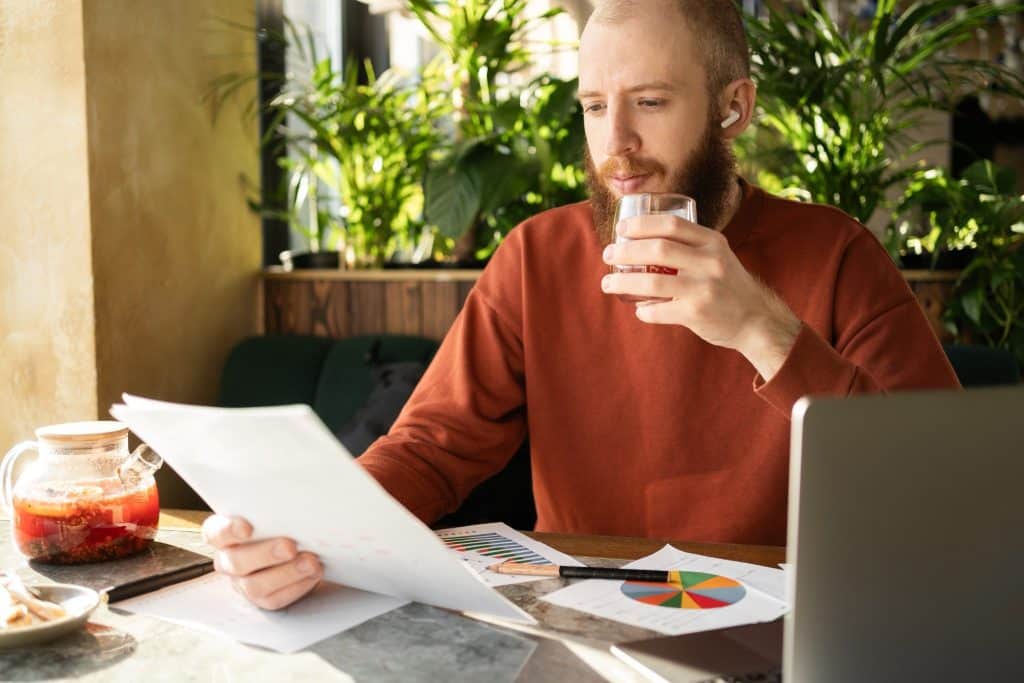 A remote worker reviewing charts in a café with tea, reflecting digital nomad productivity tips for staying organized and focused on the road.
