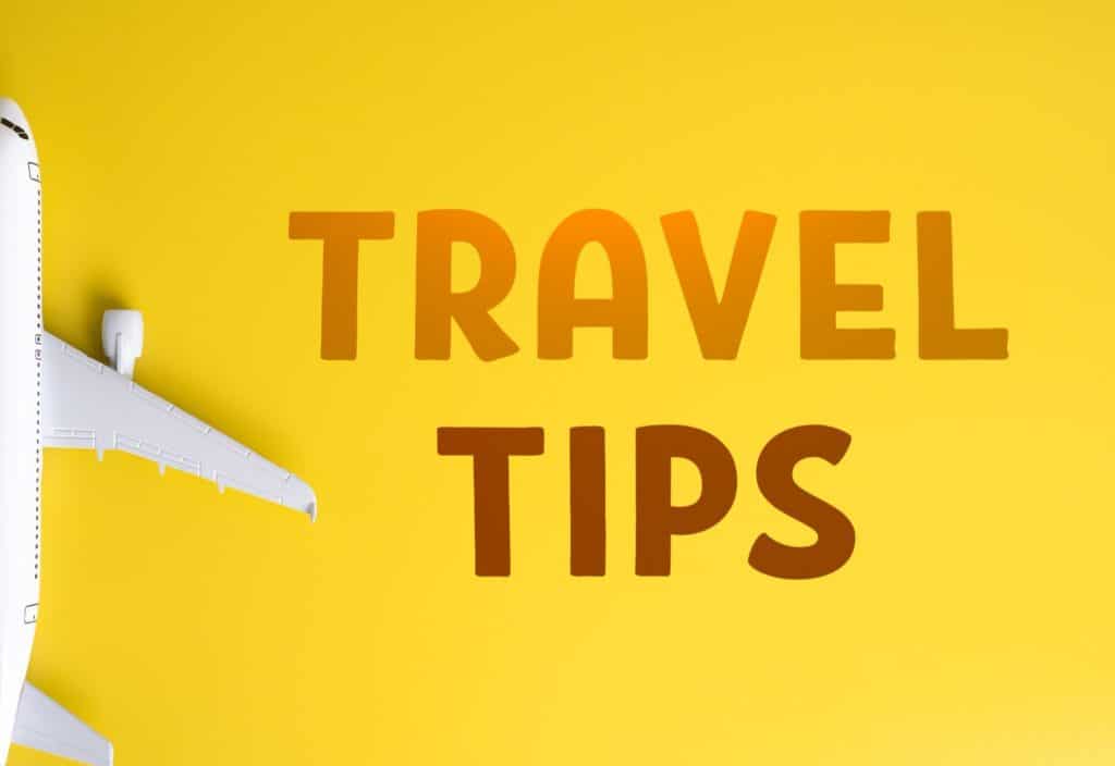 Flat lay of travel tips text and airplane model on yellow background, ideal for illustrating flight booking hacks.
