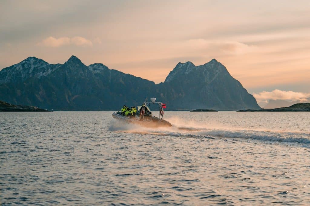 Tourists on a speedboat exploring Norway’s fjords at sunset, a thrilling adventure in a guide to Norway fjords.
