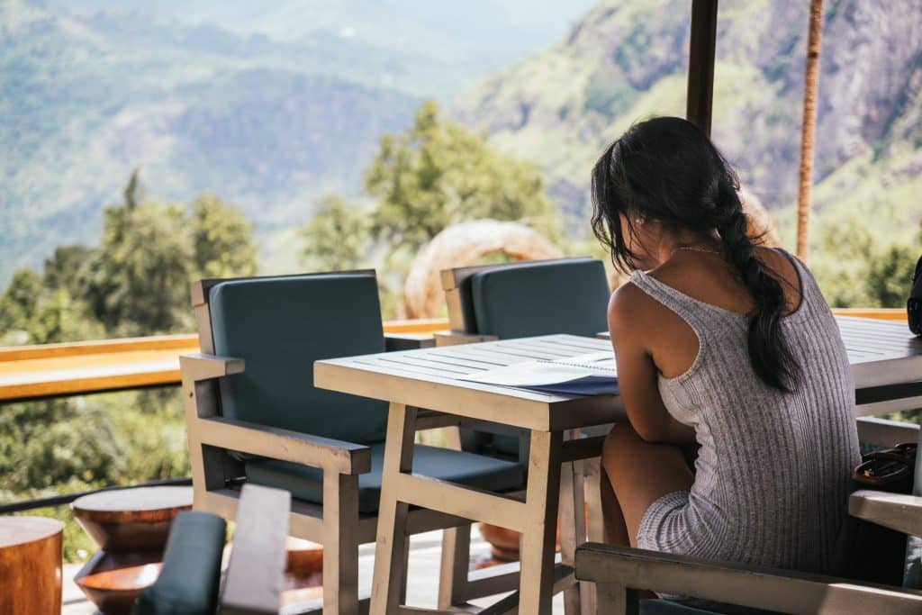 A traveler relaxing at a mountaintop café in Ella after completing the scenic Kandy to Ella train journey.