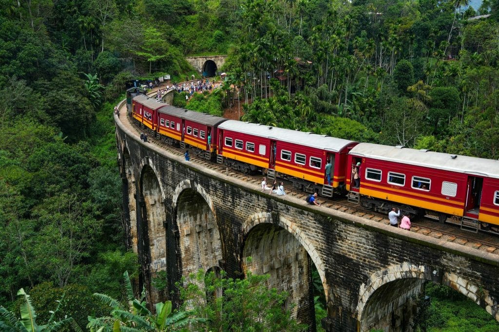 The Kandy to Ella train crossing the iconic Nine Arches Bridge surrounded by lush green jungle.