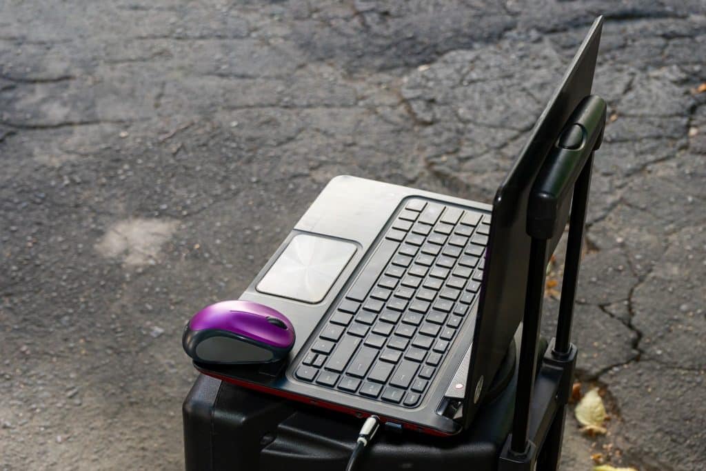 Portable office gear setup on suitcase with mouse showing ready to travel.