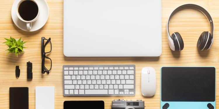 Remote work gear setup with laptop, headphones, camera, and office essentials on a wooden desk.