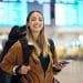 Student traveler smiling with backpack at airport using a student travel discount.