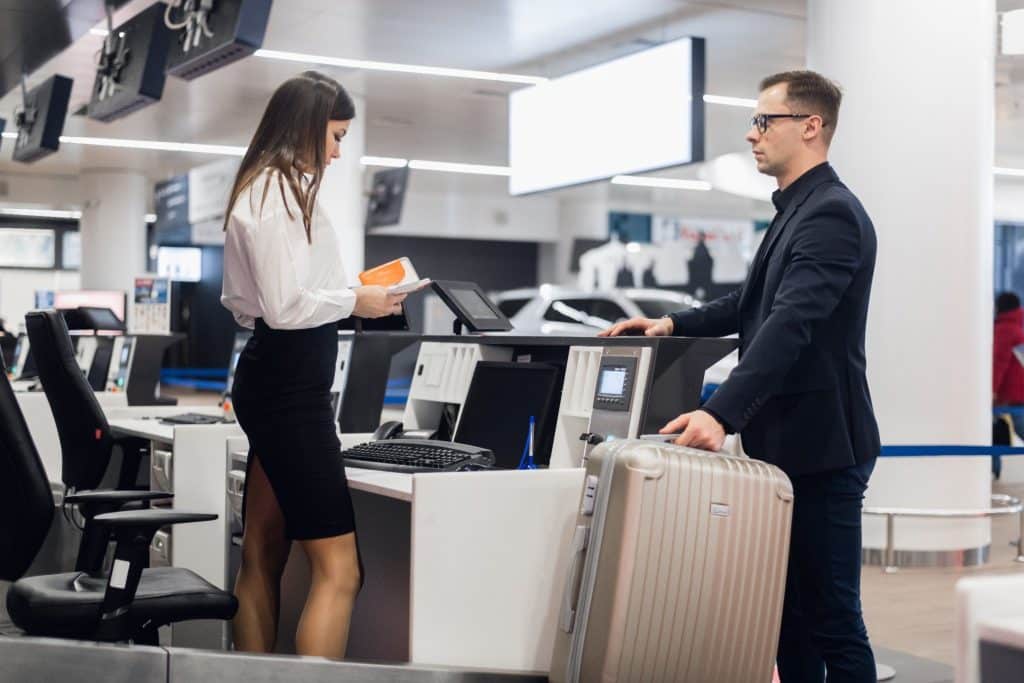 Passenger checking in luggage at the airport, highlighting how travel hacks 2025 like packing cubes and compression bags help avoid overweight fees.