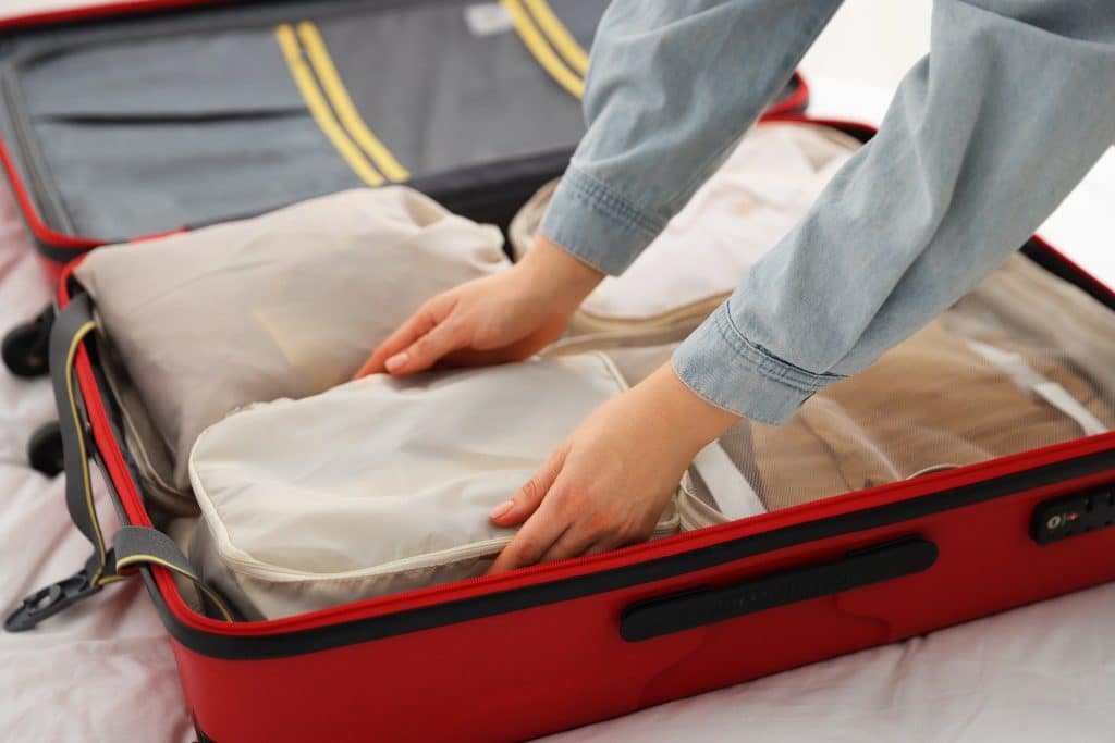 Hands arranging packing cubes inside a suitcase, demonstrating one of the most practical travel hacks 2025 for staying organized on the go.