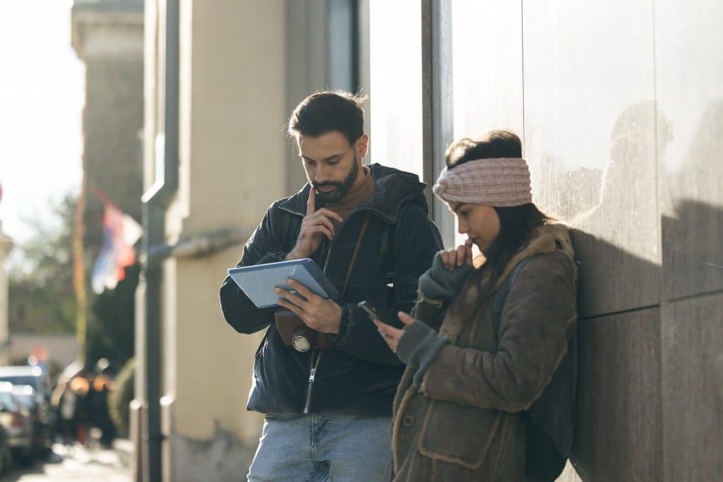 Digital nomad couple holding a tablet and phone while using Google Maps offline to navigate new neighborhoods.
