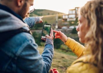 Travelers pointing at directions on a phone while using Google Maps offline in the countryside.