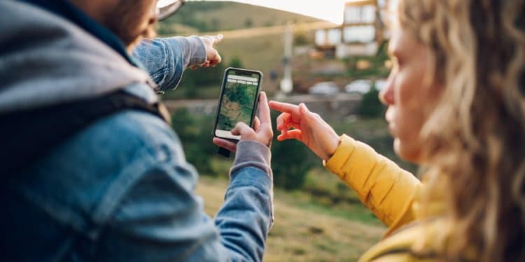 Travelers pointing at directions on a phone while using Google Maps offline in the countryside.