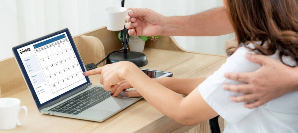 Couple pointing at laptop calendar while comparing google flights price alerts date grid
