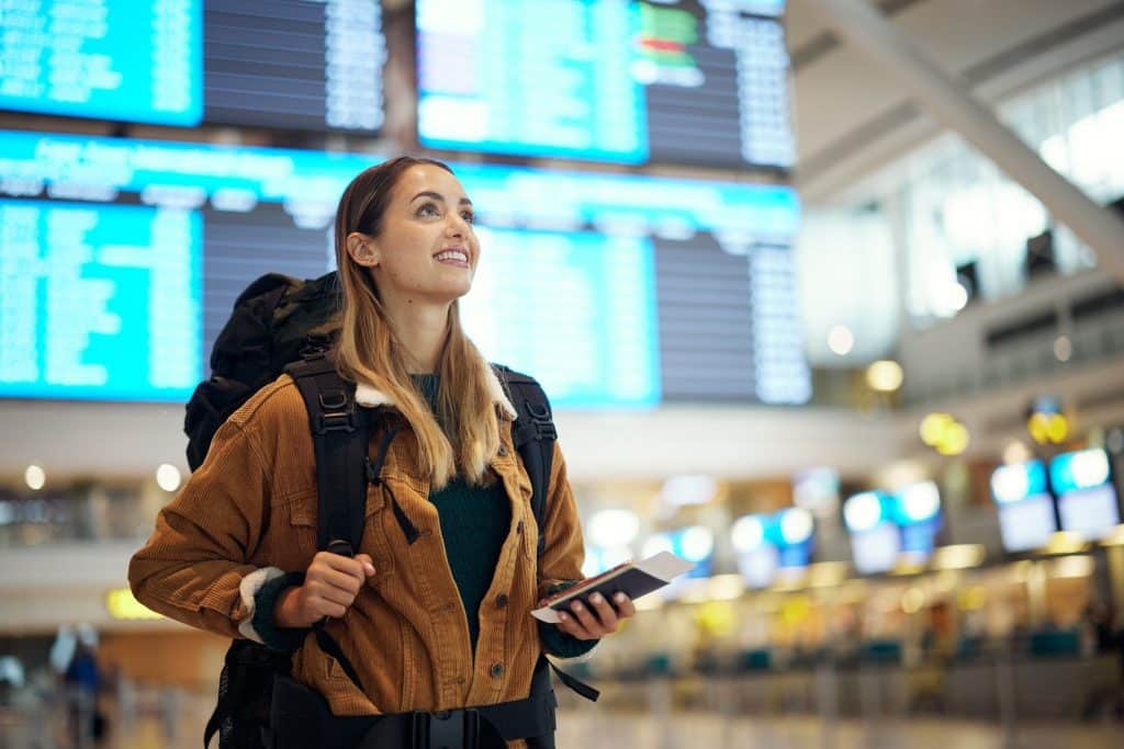 Traveler at airport planning trip after booking cheap hotel.