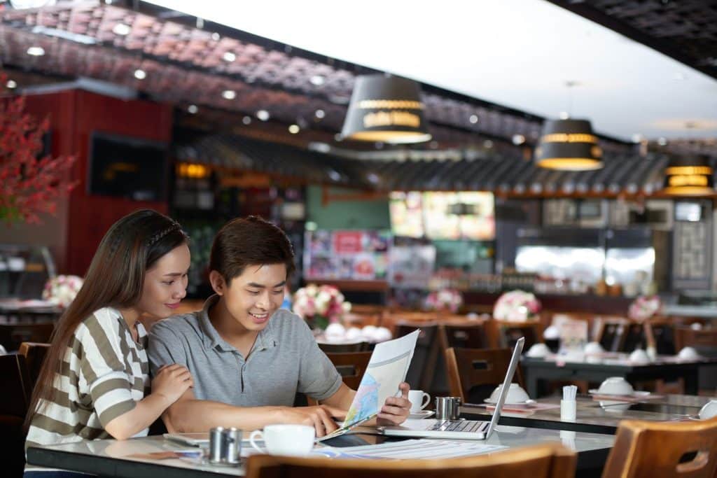 Couple checking map and laptop after booking cheap hotel.
