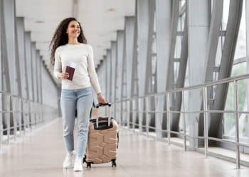 Traveler with carry-on packing tips luggage at airport gate window