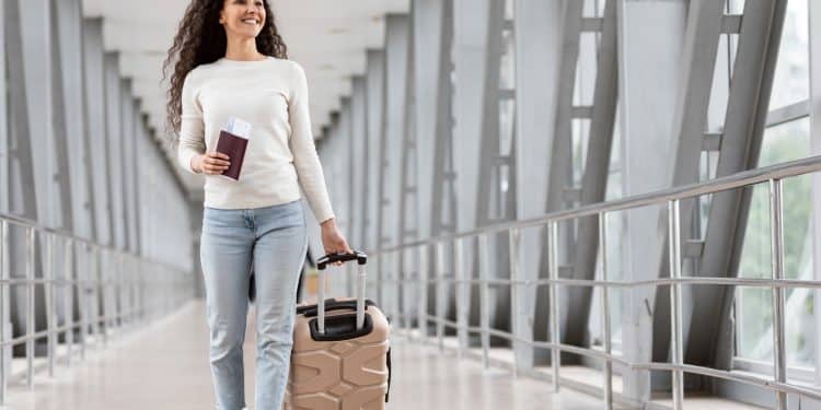 Traveler with carry-on packing tips luggage at airport gate window