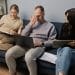 three people working on sofa looking stressed