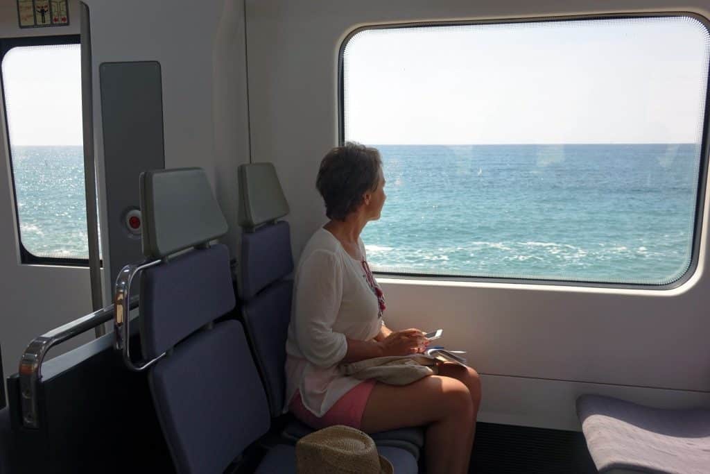 Traveler looking out train window at sea – Eurail vs point to point