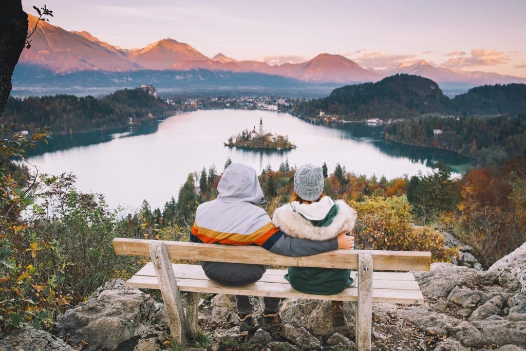 Couple enjoying a panoramic view of Lake Bled travel at sunset.