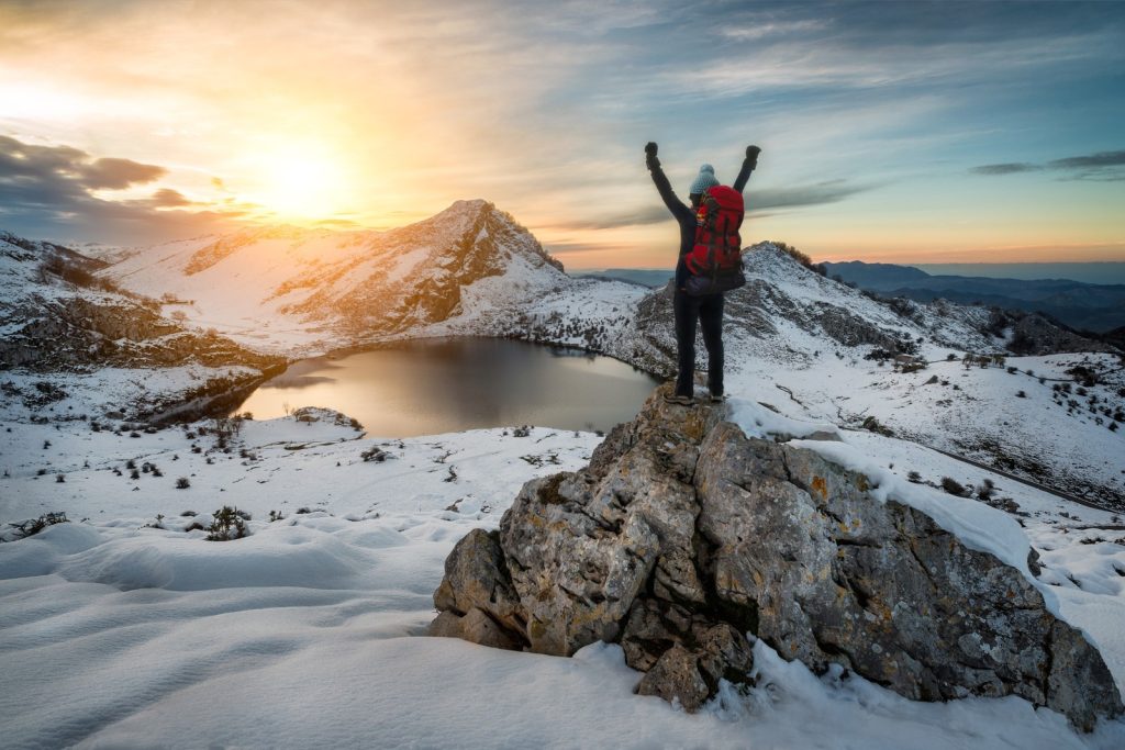 picos de europa hiking guide hiker above snowy lake at sunrise