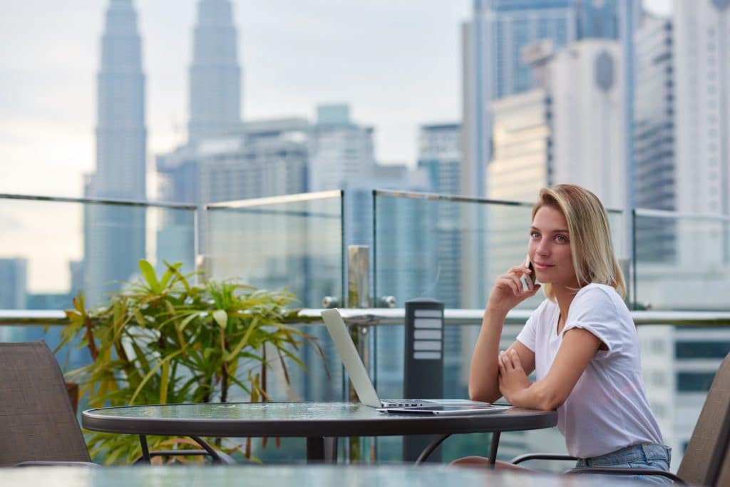 digital nomad working remotely on rooftop terrace with city skyline