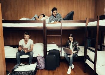 Group of travelers working and relaxing in shared dorm remote office in a hostel