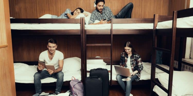 Group of travelers working and relaxing in shared dorm remote office in a hostel