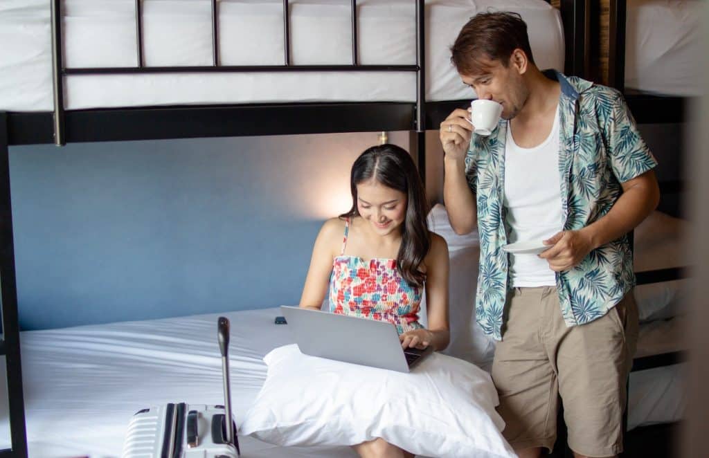 Couple balancing work and having coffee in hostel room showing remote office in a hostel