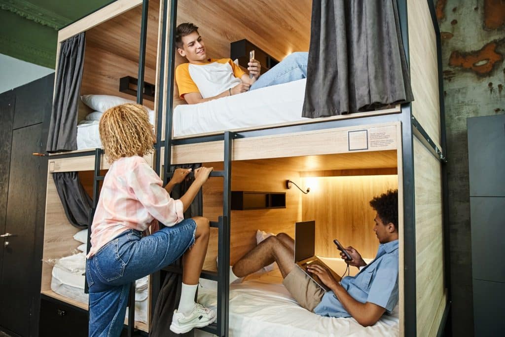 Travelers using bunk beds and laptop in remote office in a hostel