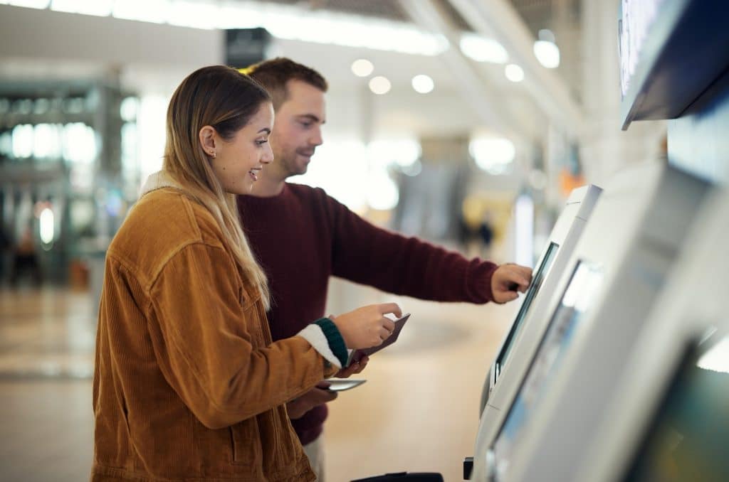 Couple using airport self check-in kiosk
