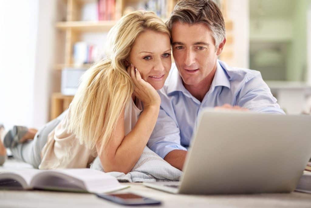 Couple planning a trip online with laptop and notes, showing the importance of careful research when building a solo travel budget.