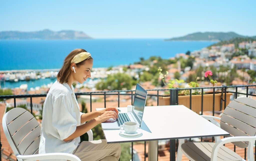 Woman stay productive while traveling with ocean view at an outdoor cafe