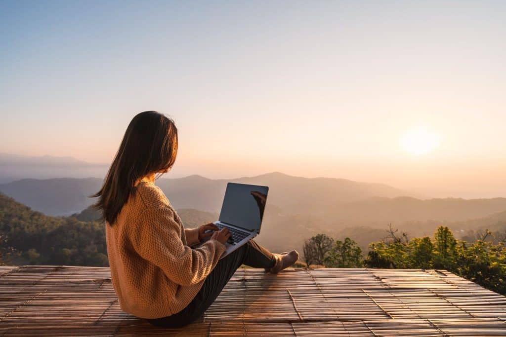 Woman working on laptop with a mountain view and staying productive