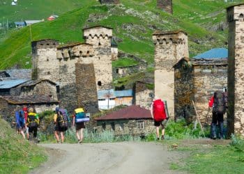 hikers walking among stone towers in Ushguli