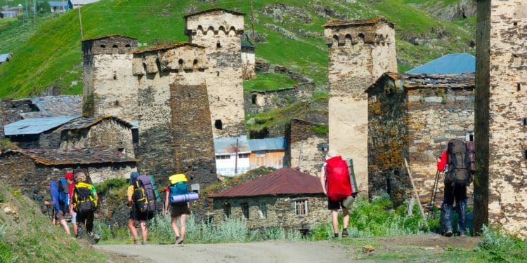 hikers walking among stone towers in Ushguli