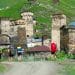 hikers walking among stone towers in Ushguli