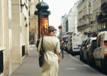 a woman walking down a street next to parked cars