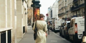 a woman walking down a street next to parked cars